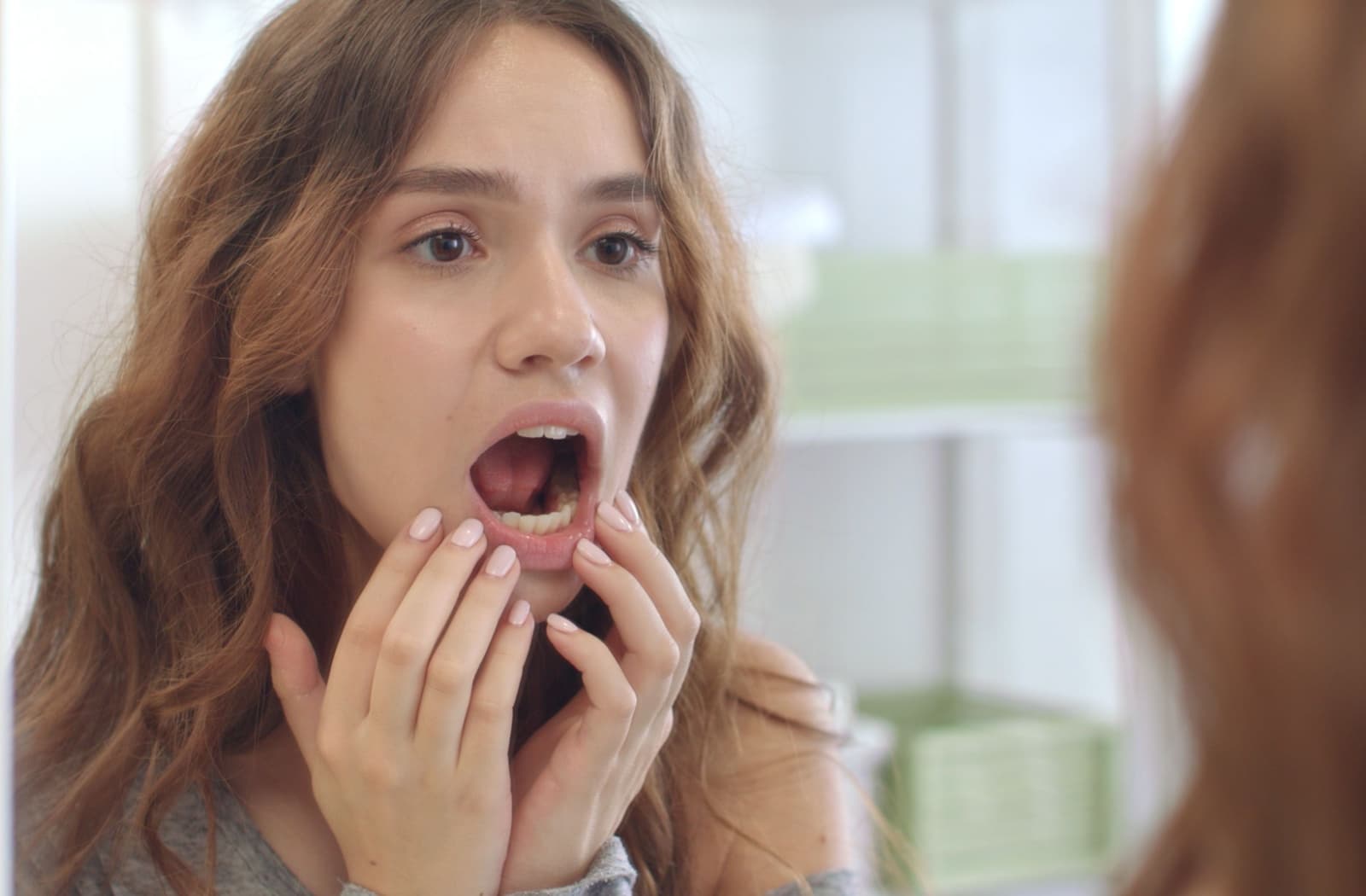 A person inspects their teeth in a mirror for signs of cavities.