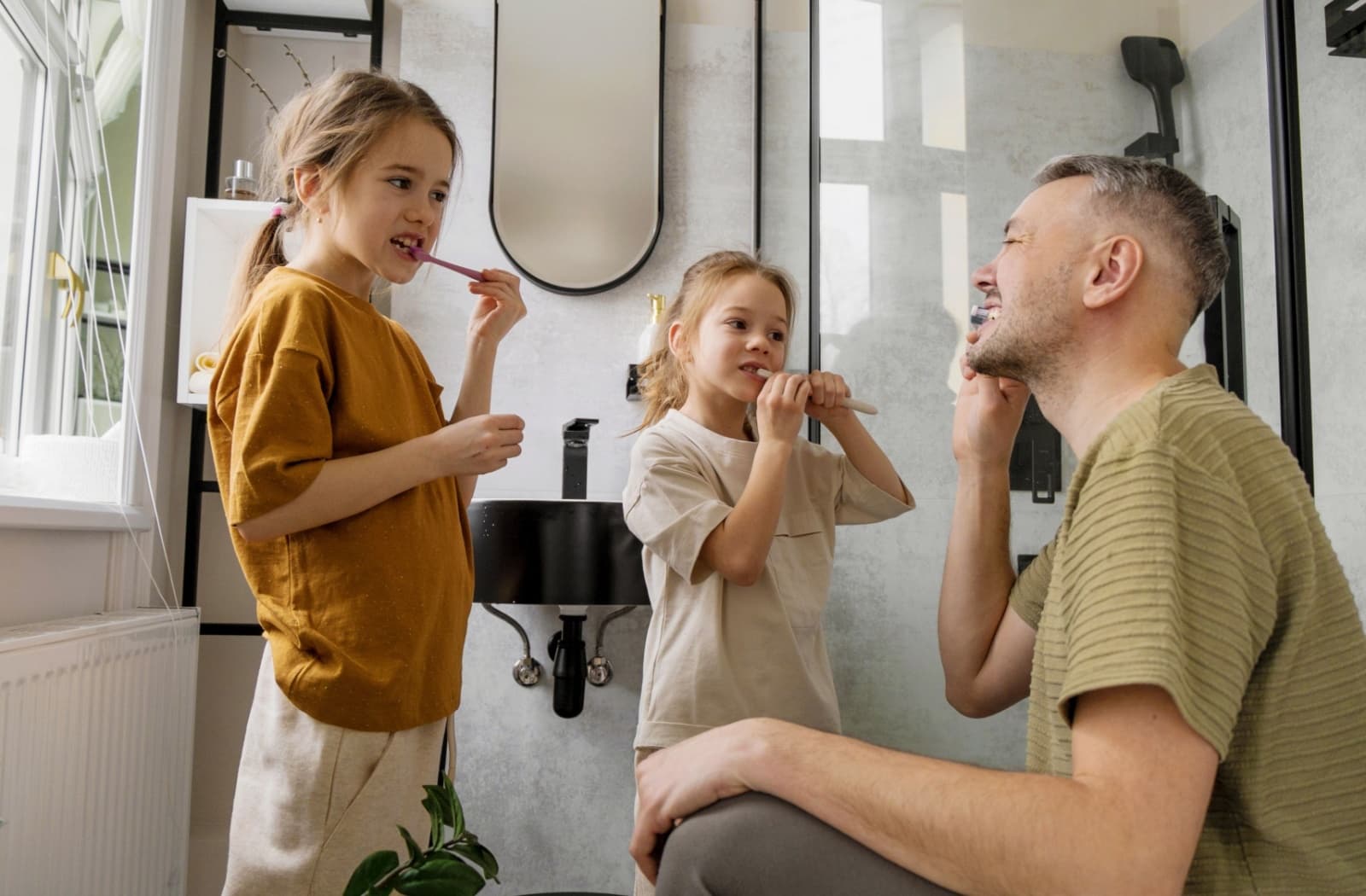 A parent shows their children how to brush their teeth properly.