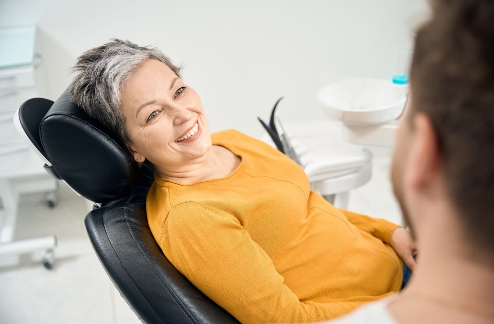 A woman smiles at her dentist from the dental chair.