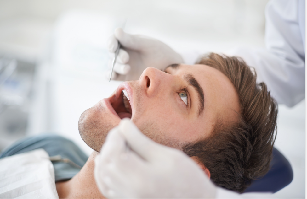 A person lying back in a dental chair during an oral examination, illustrating a professional check-up for signs of gum disease.